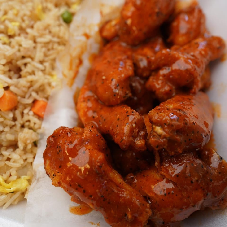 G Town Wings & Fish's spicy wings with fried rice, featuring visible carrots, peas, and egg.