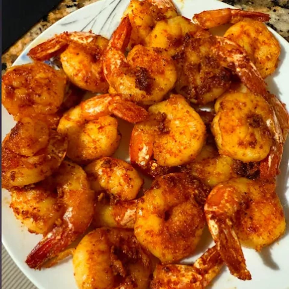 A white plate filled with golden-brown, seasoned shrimp from G Town Wings & Fish.