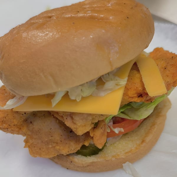 A fried fish sandwich from G Town Wings & Fish, with cheese, lettuce, tomato, and pickles.