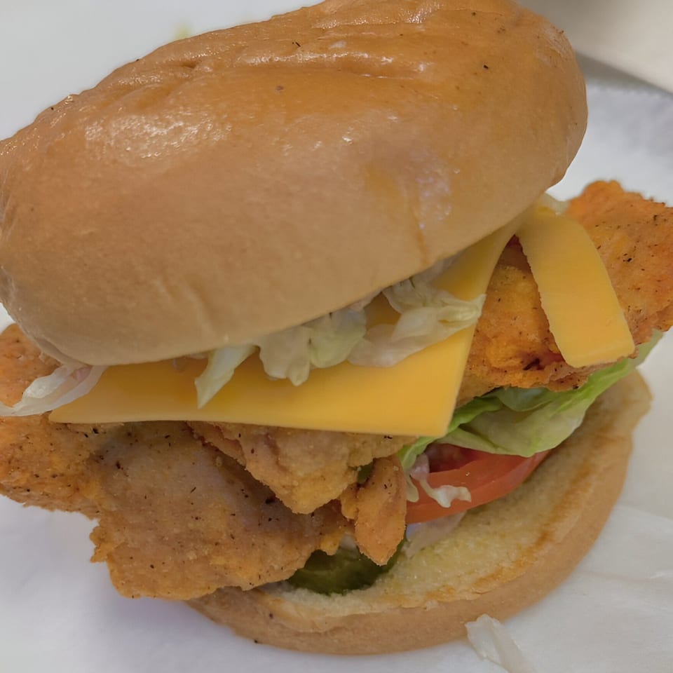 A fried fish sandwich from G Town Wings & Fish, with cheese, lettuce, tomato, and pickles.